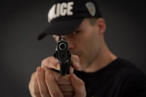 A police officer points a handgun directly at the viewer, looking serious. The text on his cap reads "POLICE."